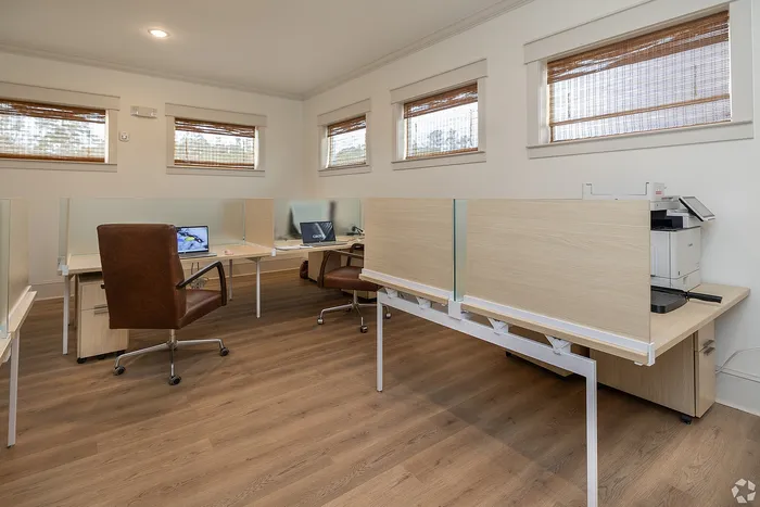 Modern office space featuring sleek wooden desks, comfortable leather chairs, and natural light filtering through stylish window blinds.
