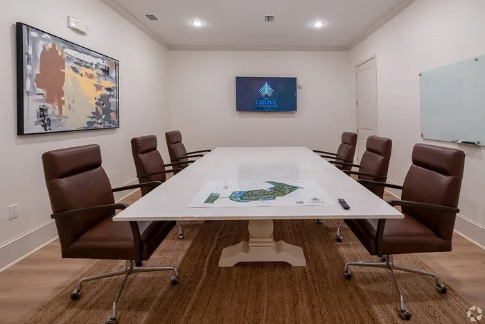 Elegant conference room with a modern design, featuring a long marble table, stylish leather chairs, abstract wall art, and a wall-mounted display, creating an ideal workspace ambiance.