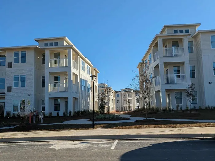Modern apartment complex showcasing elegant architecture with spacious balconies under a clear blue sky.