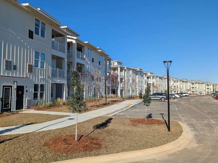 Bright, modern apartment complex with lush landscaping, ample parking, and sleek architectural design.