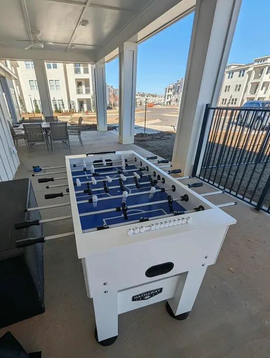 Inviting outdoor lounge area featuring a modern foosball table, overlooking stylish apartment buildings.
