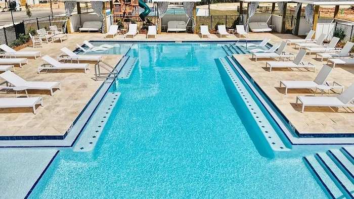 Luxurious outdoor swimming pool surrounded by chic lounge chairs and cozy cabanas, perfect for relaxing in the sun.