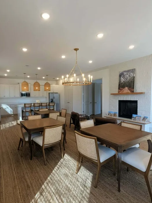 Chic and spacious dining area with elegant chandelier, modern open kitchen, and cozy seating in a beautifully lit apartment.
