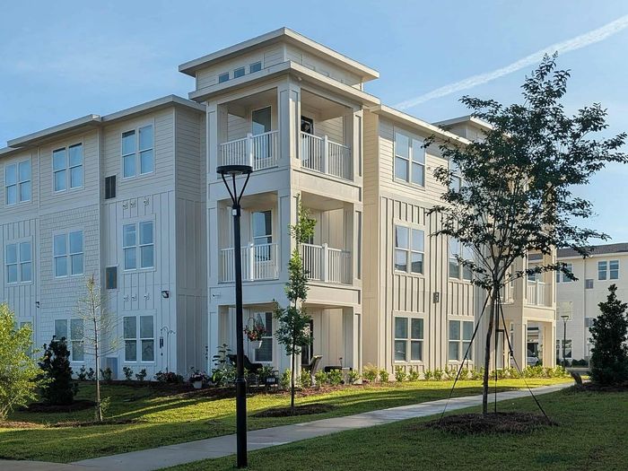 Elegant modern apartment building with balconies and lush landscaped surroundings, offering a serene living environment.