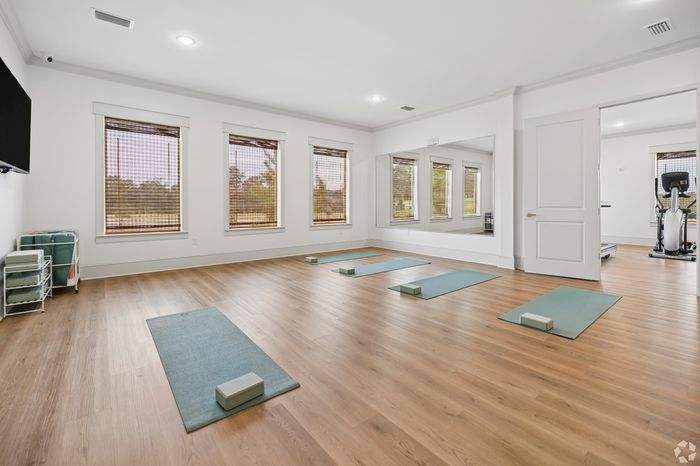 Spacious and serene yoga room with hardwood floors, large mirrors, and natural light, perfect for relaxation and exercise.
