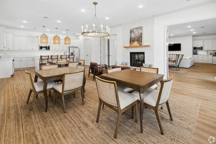 Elegant open-plan kitchen and dining area featuring a cozy fireplace, sleek white cabinetry, and stylish pendant lighting.