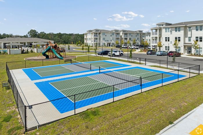 Vibrant community amenities featuring modern tennis courts and a children's playground surrounded by stylish apartment buildings and lush greenery.