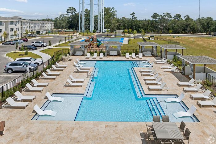 Luxurious apartment complex featuring a pristine swimming pool surrounded by elegant lounge chairs, shaded cabanas, and a stylish outdoor play area, perfect for relaxation and leisure.