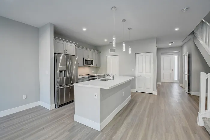 Modern kitchen with sleek stainless steel appliances, elegant pendant lighting, and a spacious white quartz countertop island.