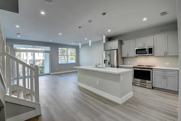 Contemporary open-concept kitchen and living area with sleek hardwood floors, modern appliances, and ample natural light.