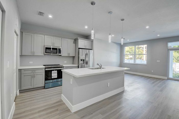 Modern open-concept kitchen with sleek stainless steel appliances and elegant pendant lighting.