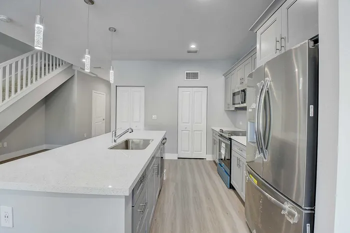 Sleek modern kitchen featuring stainless steel appliances, elegant quartz countertops, and stylish pendant lighting.