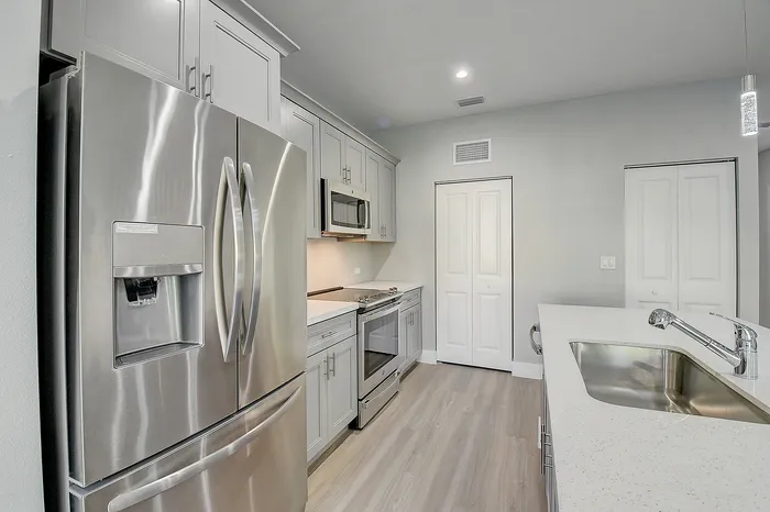 Modern kitchen featuring sleek stainless steel appliances, elegant white cabinetry, and a polished countertop for a sophisticated look.
