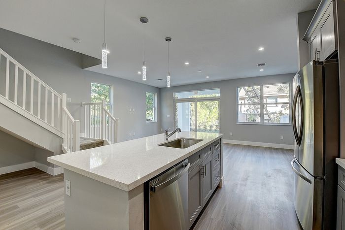 Modern open-concept living area featuring a sleek kitchen island, elegant pendant lighting, and large windows for natural light.
