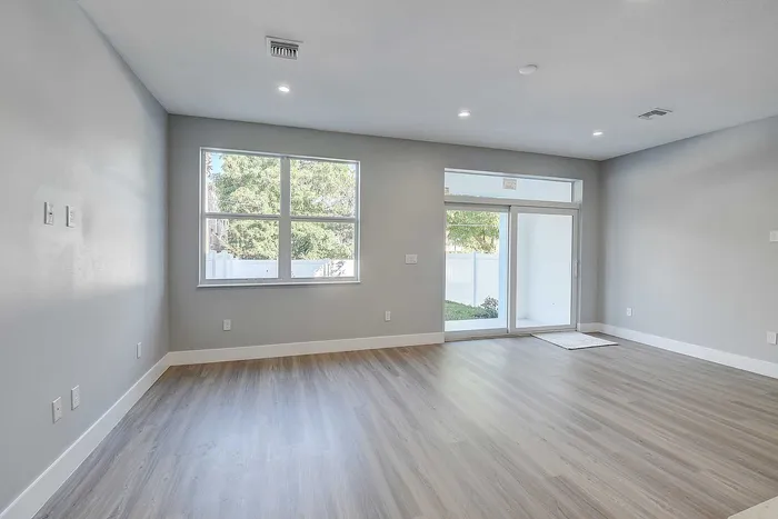 Bright and spacious open living area featuring elegant wood flooring, large windows, and abundant natural light.