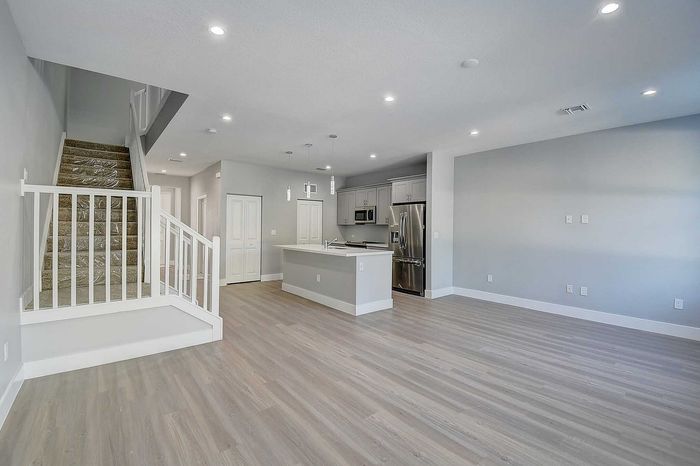 Modern open-concept living area with sleek kitchen, elegant wooden floors, and contemporary staircase design.