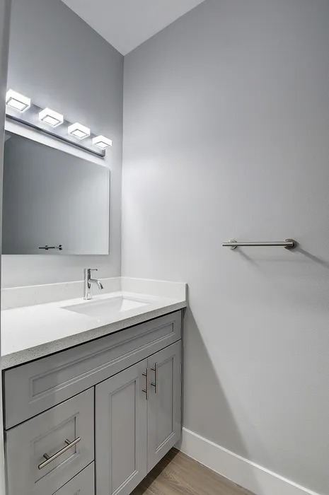 Modern bathroom with sleek white vanity, quartz countertop, and stylish lighting fixtures.
