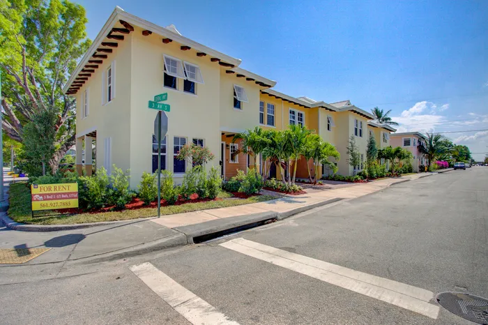 Charming yellow townhouse for rent with lush landscaping on a sunny corner lot, featuring 3 beds and 2.5 baths.