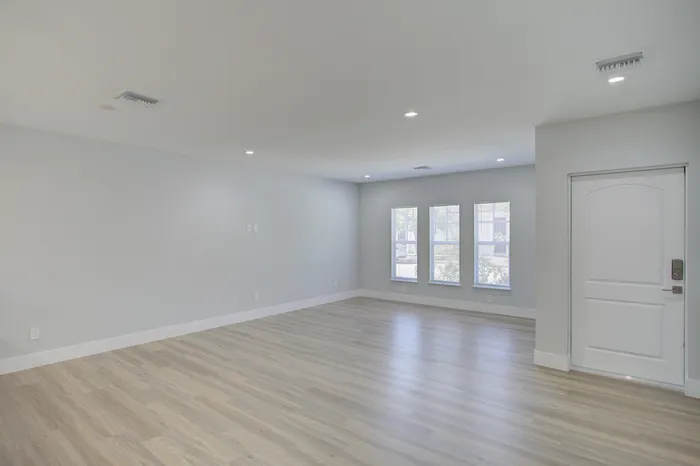 Spacious living area with elegant hardwood flooring and abundant natural light streaming through large windows.