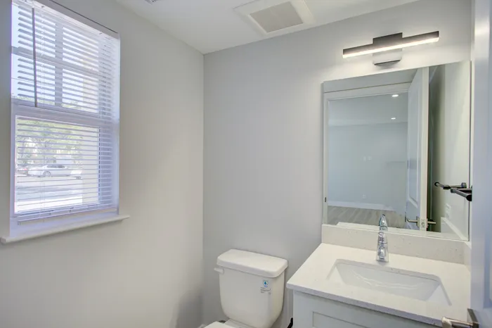 Bright and modern bathroom with sleek fixtures, a large window, and ample natural light.