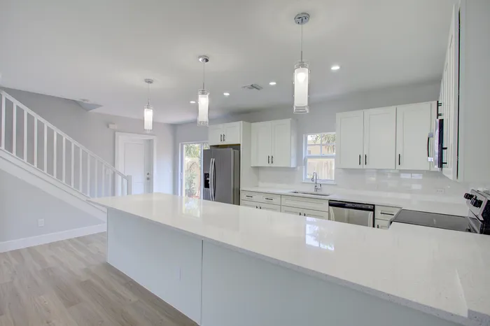 Bright and modern kitchen with sleek white cabinetry, sparkling countertops, and elegant pendant lighting, perfect for culinary adventures.