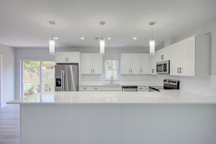 Modern kitchen design with sleek white cabinetry, stainless steel appliances, and elegant pendant lighting.