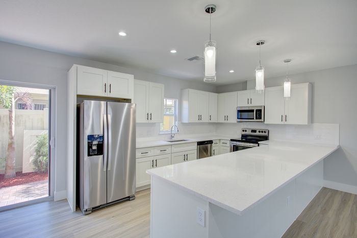 Sleek modern kitchen with stainless steel appliances, elegant white cabinetry, and chic pendant lighting.
