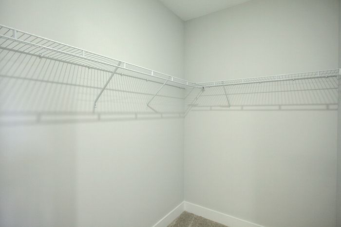 Spacious walk-in closet with sleek wire shelving and a soft carpeted floor offering ample storage space.