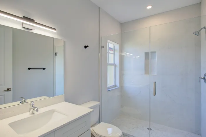 Elegant bathroom with a sleek glass shower, modern vanity, and bright natural lighting.