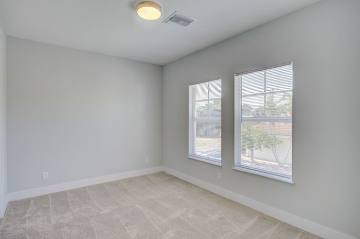 Bright and spacious bedroom with large windows and plush carpeting, perfect for relaxing and enjoying natural light.