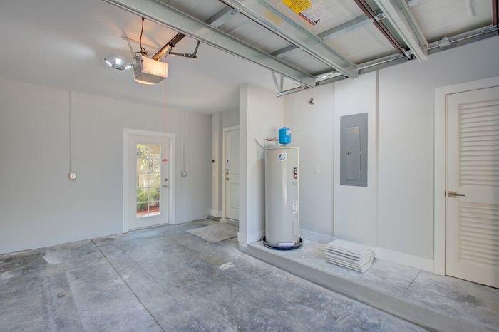 Spacious modern garage with a sleek water heater, abundant natural light, and convenient access to outdoor greenery.