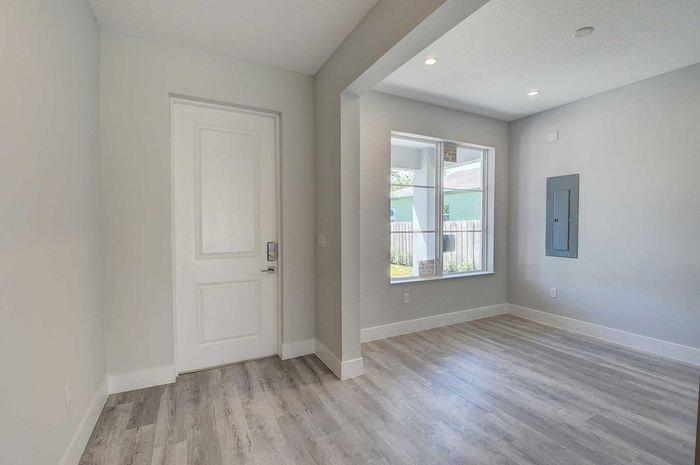Bright entryway with modern wood flooring, large window for natural light, and sleek recessed lighting.