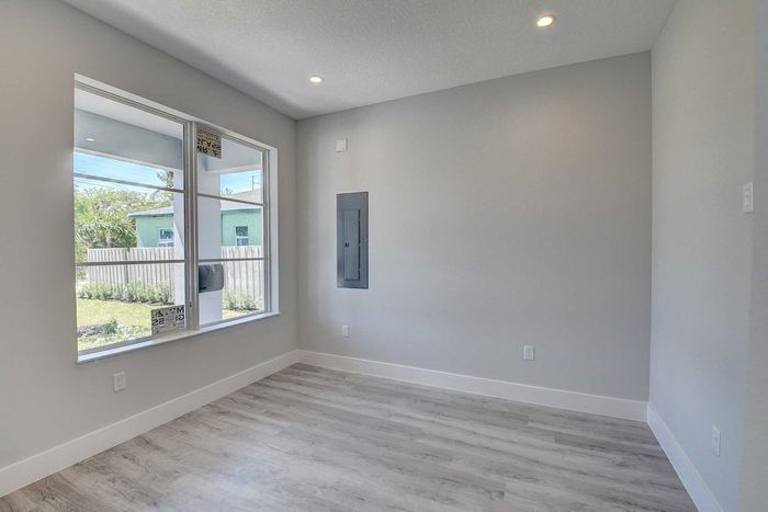 Bright and airy room with large windows and modern grey flooring, perfect for customizable living or office space.