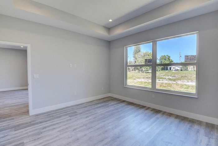 Bright and spacious room with modern flooring and large window offering serene views of lush greenery.