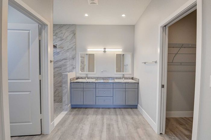 Elegant bathroom with dual sinks, sleek marble accents, and a spacious walk-in closet in a modern apartment.