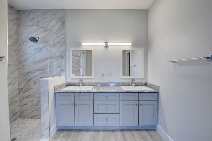 Elegant bathroom with dual sinks, marble shower, and modern design elements.