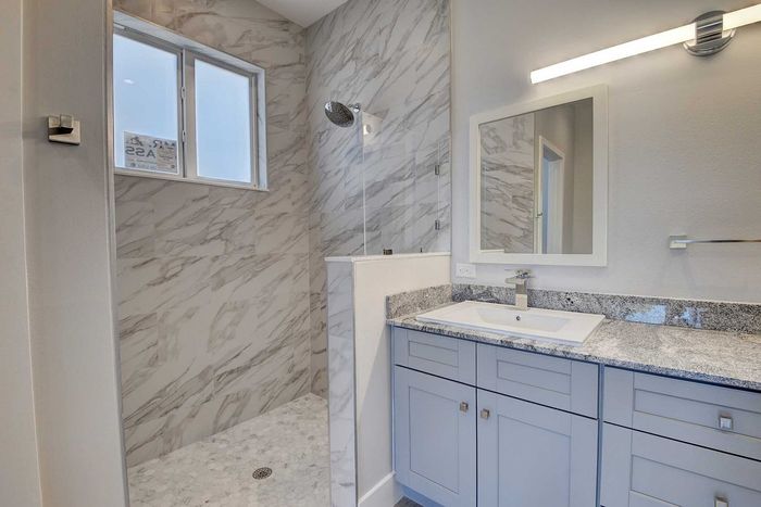 Elegant bathroom with marble accents, featuring a modern walk-in shower, granite countertop, and spacious vanity.