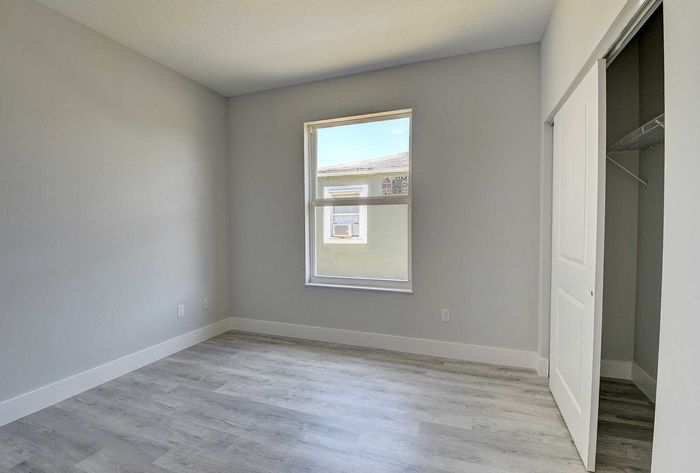 Bright and airy bedroom with large window, modern flooring, and spacious closet, perfect for personalization.