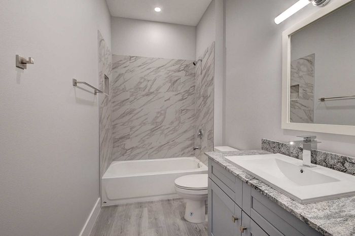 Elegant bathroom featuring a sleek vanity with a granite countertop, modern fixtures, and a marble-tiled shower area.