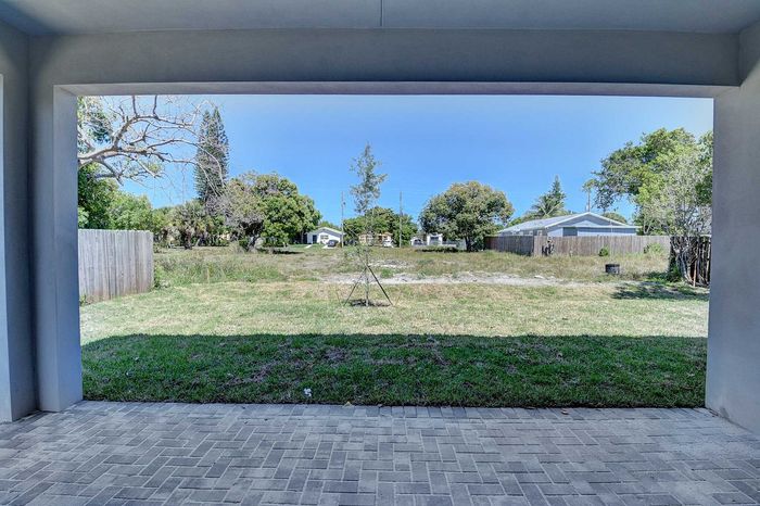 Inviting backyard view from a covered patio, featuring lush greenery and serene open space.