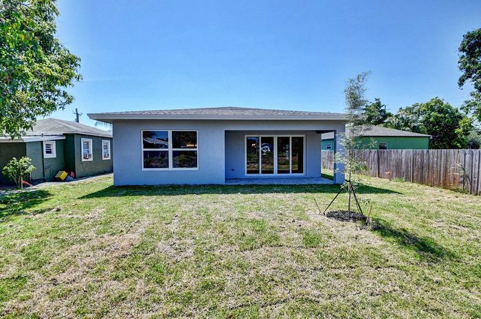 Charming modern home exterior with spacious grassy yard, large windows, and bright blue sky.