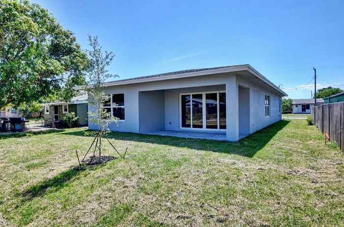 Lovely modern home with a spacious backyard, large windows, and a charming patio, perfect for outdoor relaxation.