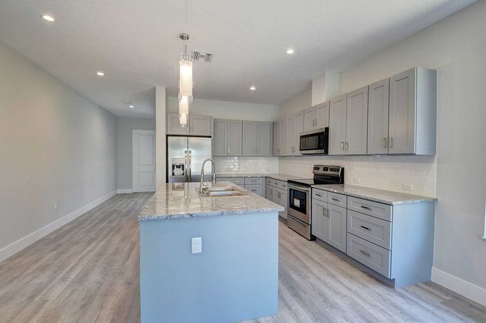 Gorgeous modern kitchen with sleek gray cabinets, an elegant island, and stainless steel appliances, offering plenty of space and style.