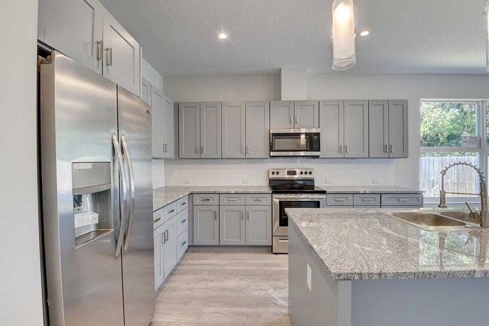 Modern kitchen with sleek stainless steel appliances, elegant gray cabinetry, granite countertops, and a spacious island.