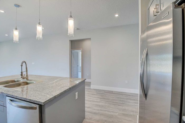 Modern kitchen with sleek granite countertops, stainless steel appliances, and elegant pendant lighting, ideal for contemporary living.