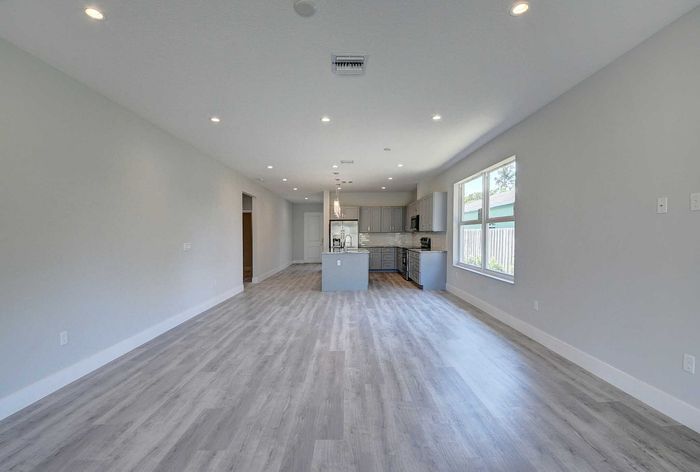 Spacious open-concept living area with modern kitchen, sleek gray cabinetry, and elegant hardwood flooring.