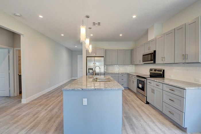 Modern kitchen with sleek gray cabinetry, granite countertops, and stainless steel appliances, ideal for culinary enthusiasts.