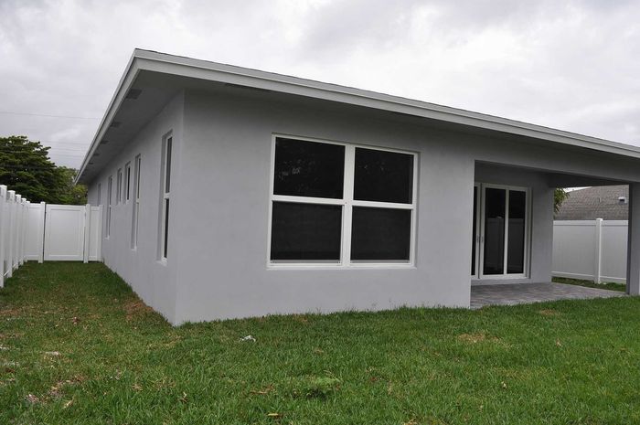 Modern single-story house with sleek gray exterior, large windows, and inviting backyard, perfect for enjoying outdoor living.