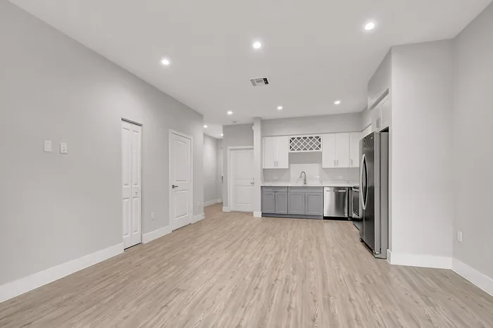 Chic apartment interior showcasing a modern kitchen with stainless steel appliances, elegant cabinetry, and sleek lighting, accentuated by beautiful wood flooring.