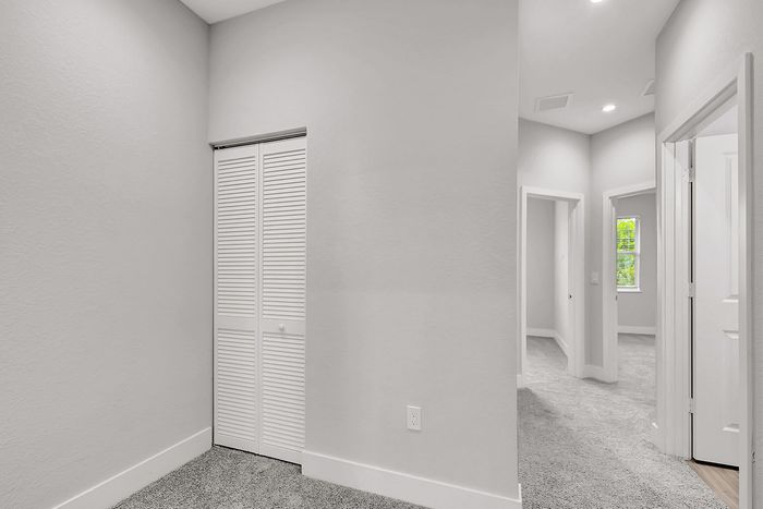 Bright and inviting hallway with plush carpeting, showcasing modern design and ample natural light.